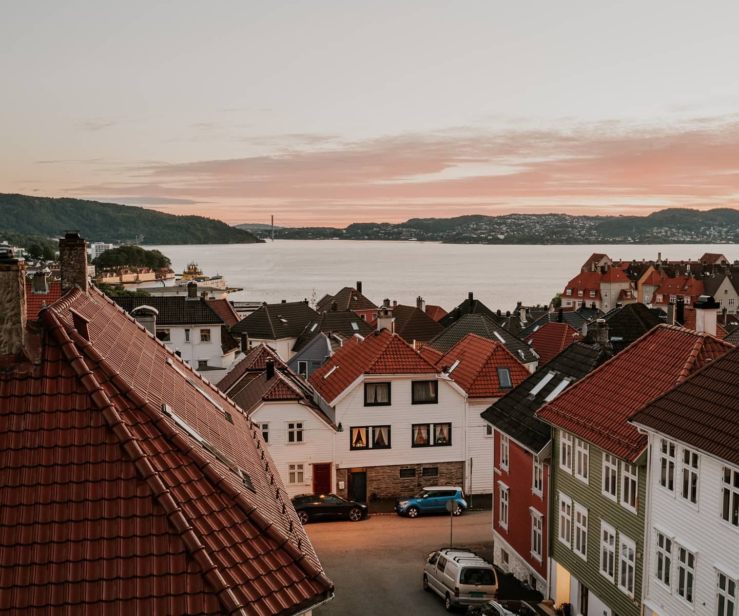 View over rooftops and traditional wooden houses by the waterfront in a Norwegian coastal town.