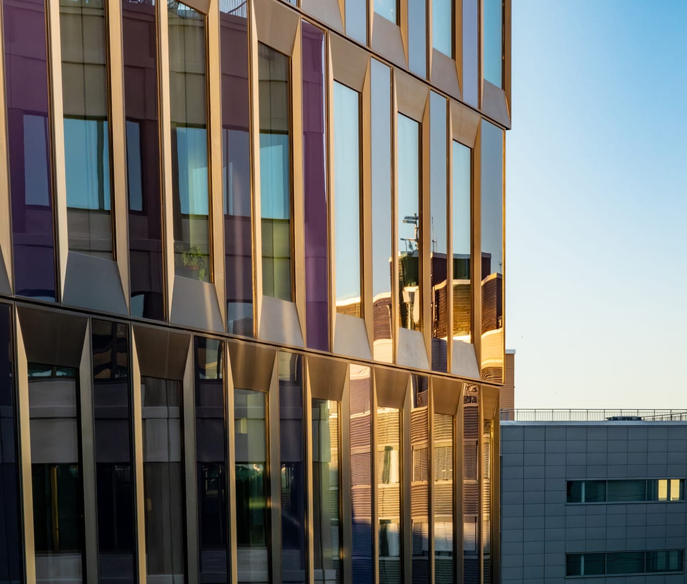 Modern office building with a glass façade reflecting the surrounding cityscape.