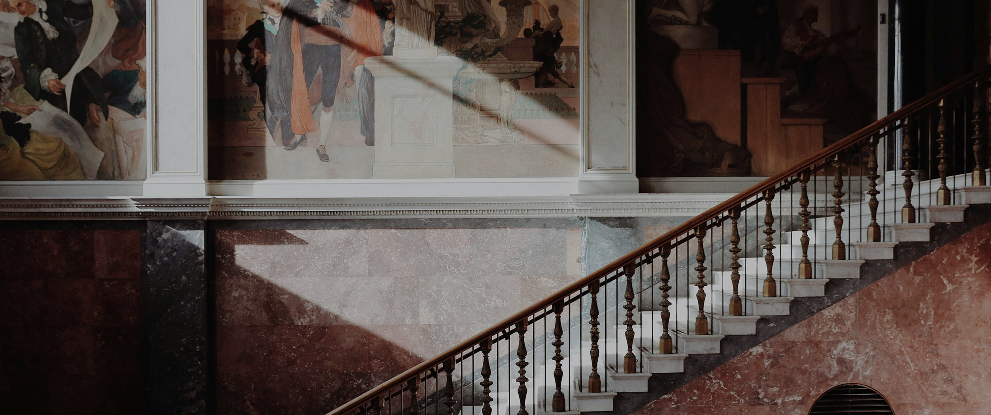 Interior with a marble staircase and decorative wall paintings.