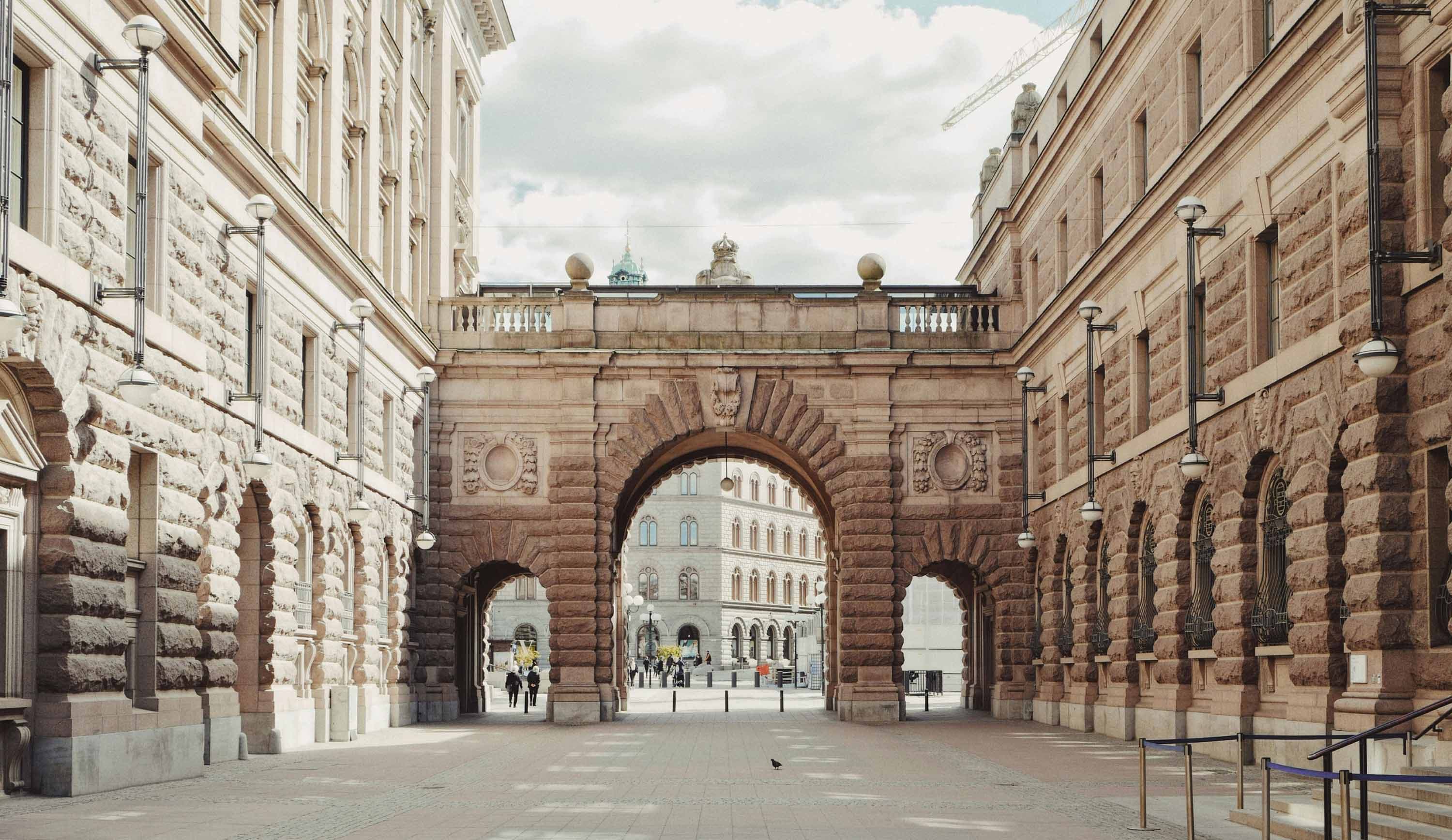 Historic archway between stone buildings in central Stockholm.