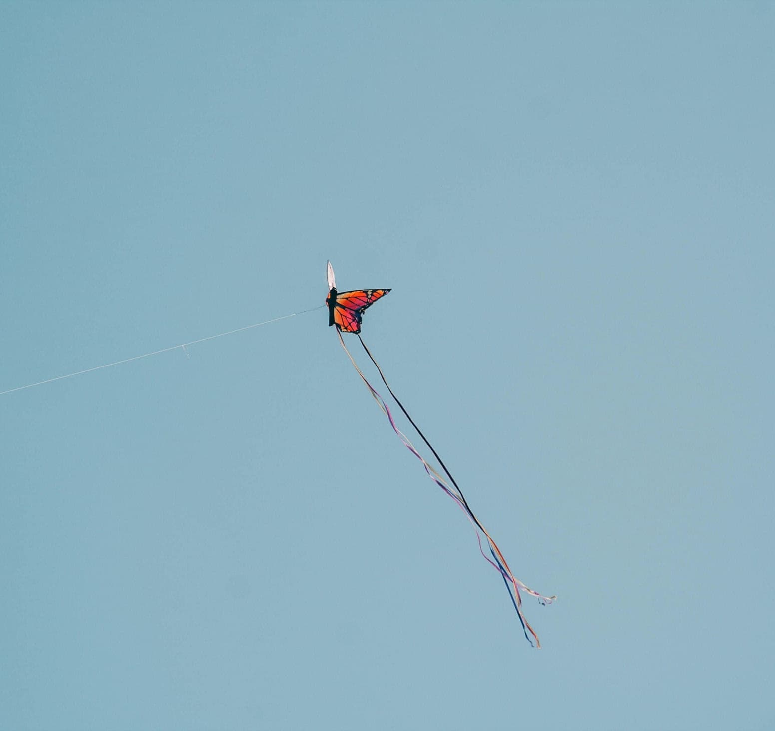 Colourful kite soaring against a blue summer sky.